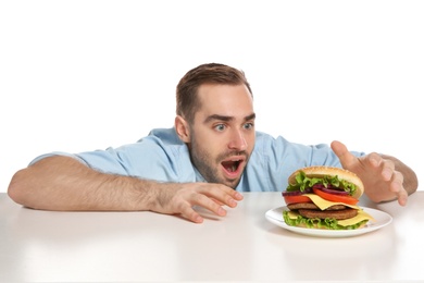 Photo of Young hungry man with tasty burger on white background