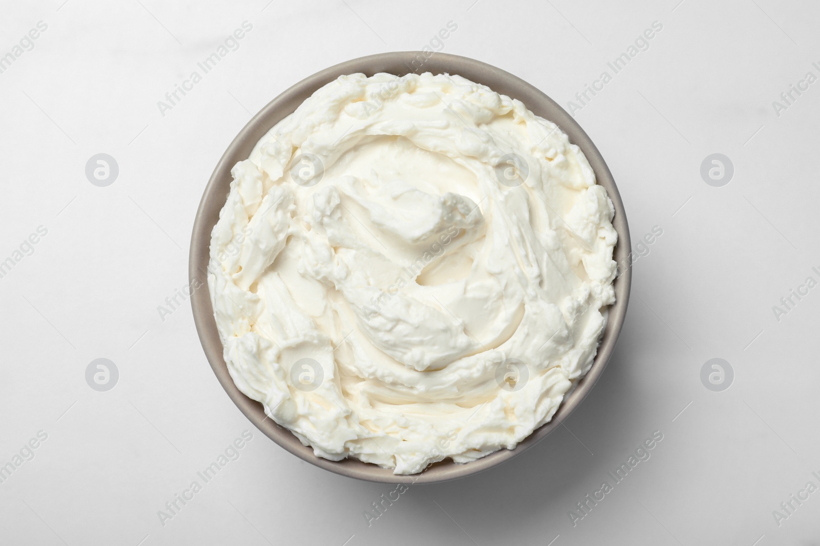 Photo of Bowl of tasty cream cheese on white table, top view