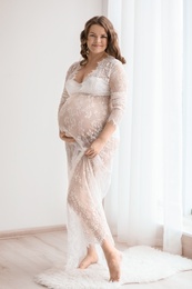 Young pregnant woman in elegant dress at home