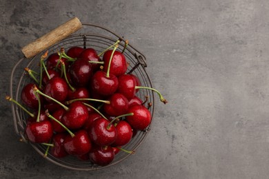 Photo of Metal basket with ripe sweet cherries on grey table, top view. Space for text