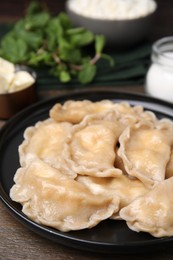 Photo of Plate of delicious dumplings (varenyky) with cottage cheese on wooden table, closeup