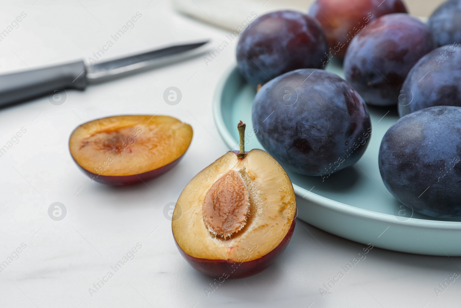 Photo of Tasty ripe plums on white table, closeup