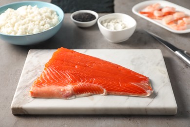 Fresh salmon and other ingredients for sushi on grey table, closeup