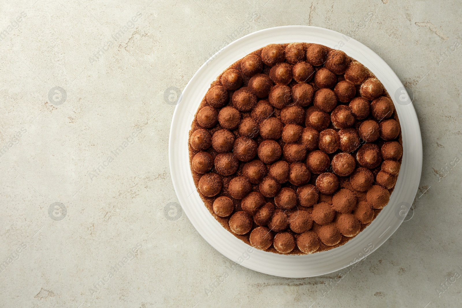 Photo of Delicious tiramisu cake with cocoa powder on light textured table, top view. Space for text