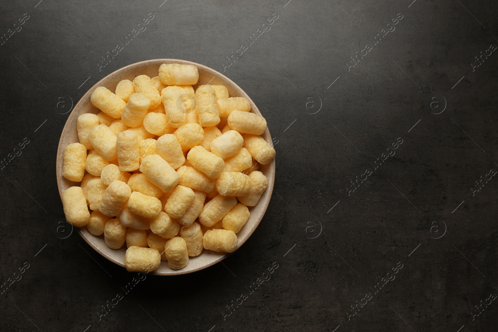 Photo of Plate of corn sticks on dark grey table, top view. Space for text