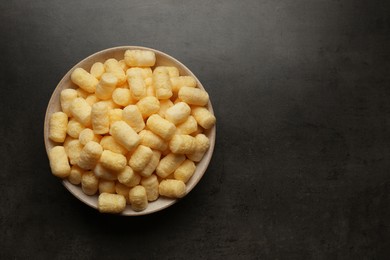 Plate of corn sticks on dark grey table, top view. Space for text
