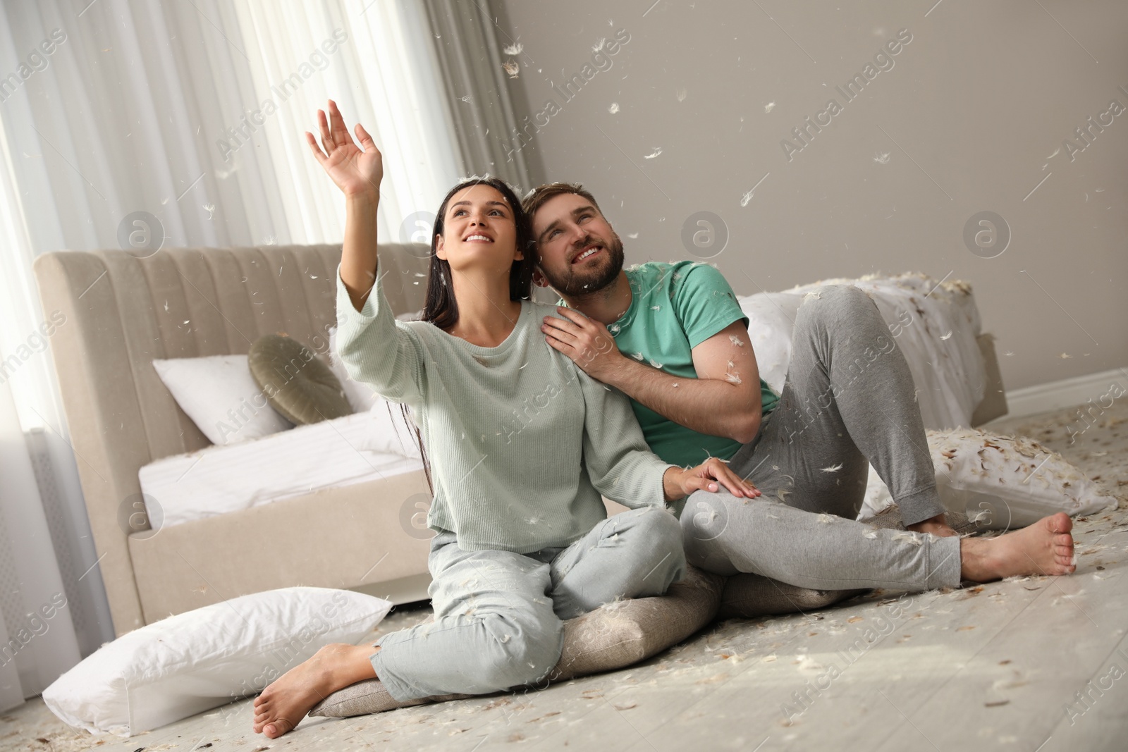 Photo of Happy young couple resting after fun pillow fight in bedroom