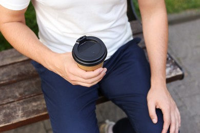 Photo of Coffee to go. Man with paper cup of drink outdoors, closeup