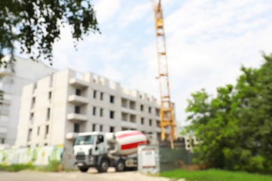 Photo of Blurred view of unfinished building and concrete mixer truck outdoors