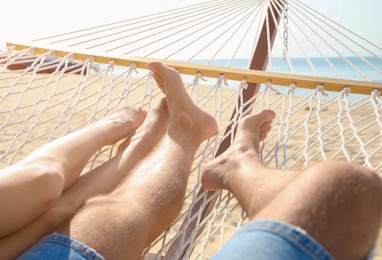 Photo of Young couple relaxing in hammock on beach, closeup