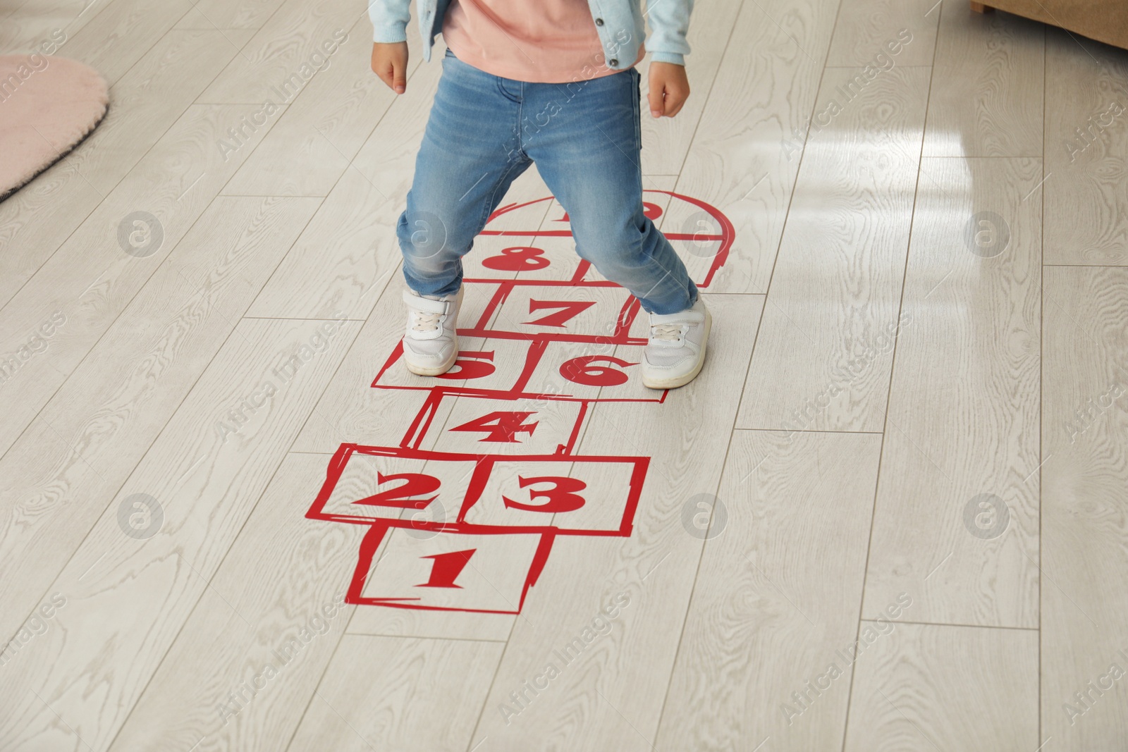 Photo of Little girl playing hopscotch at home, closeup