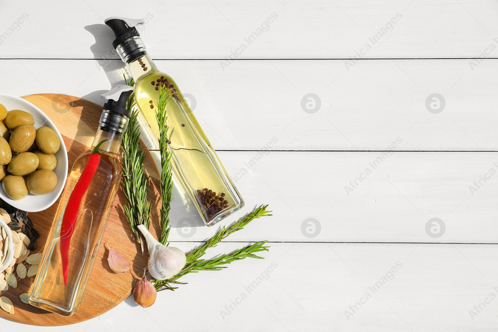 Photo of Different cooking oils and ingredients on white wooden table, flat lay. Space for text