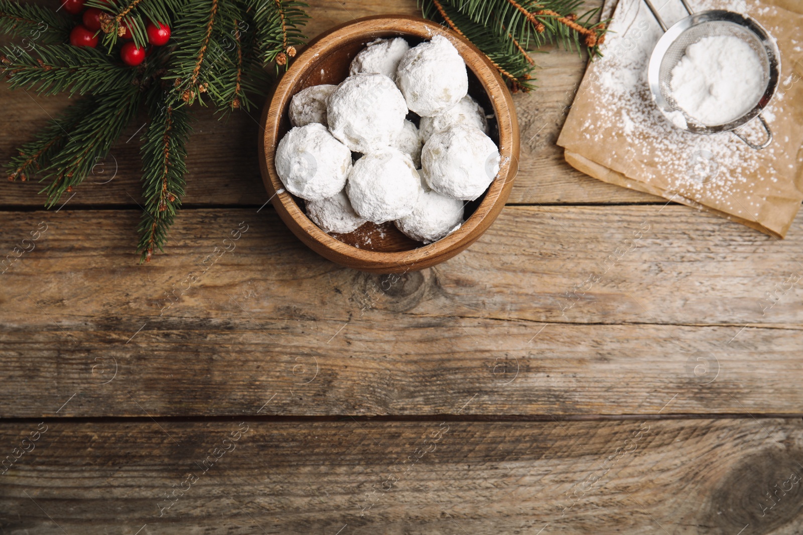 Photo of Tasty Christmas snowball cookies in bowl on wooden table, flat lay. Space for text