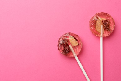 Photo of Sweet colorful lollipops with berries on pink background, flat lay. Space for text