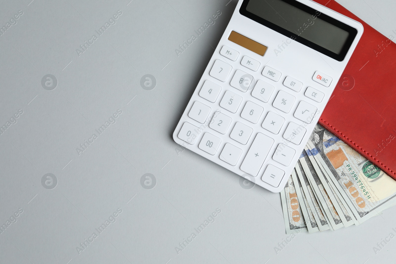 Photo of Money exchange. Dollar banknotes and calculator on gray background, top view. Space for text