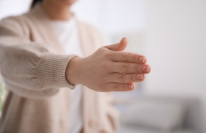 Photo of Young woman offering handshake indoors, closeup view