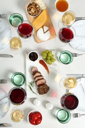 Wine and snacks served for dinner on light table, flat lay