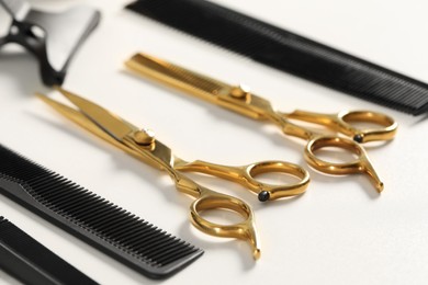 Photo of Hairdresser tools. Different scissors and combs on white table, closeup