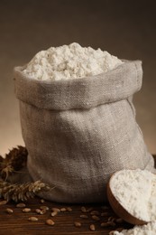 Wheat flour, grains and spikes on wooden table, closeup