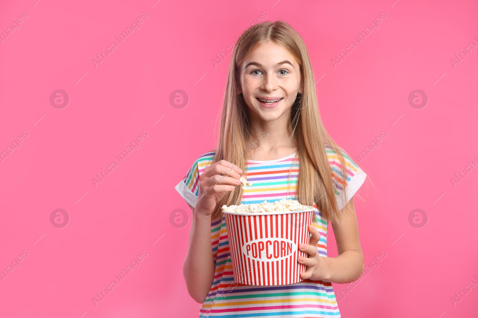 Photo of Teenage girl with popcorn during cinema show on color background