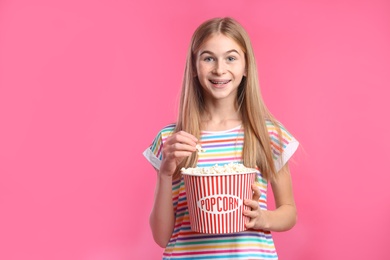Photo of Teenage girl with popcorn during cinema show on color background