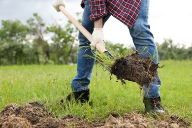 Worker digging soil with shovel outdoors, closeup