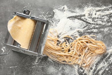 Photo of Pasta maker with dough on table, top view