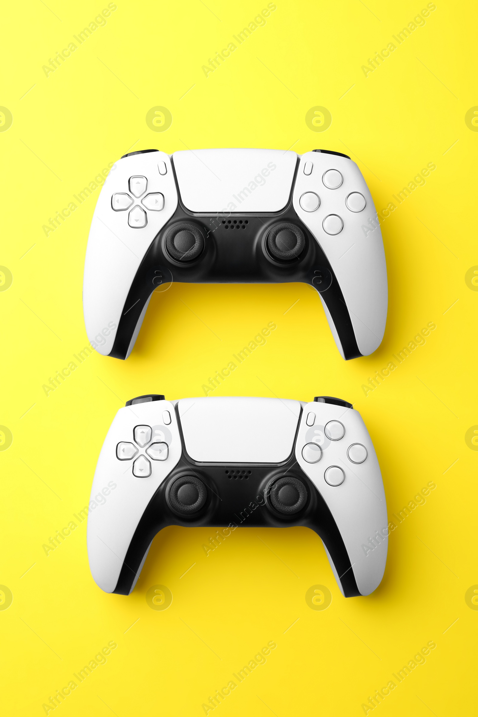 Photo of Wireless game controllers on yellow background, flat lay