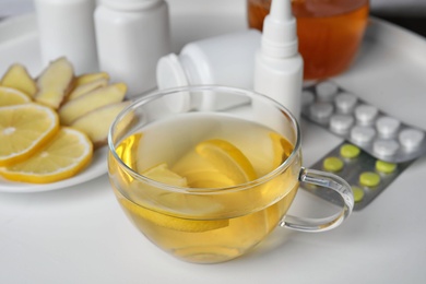 Photo of Glass cup of hot tea with lemon and different cold remedies on white table