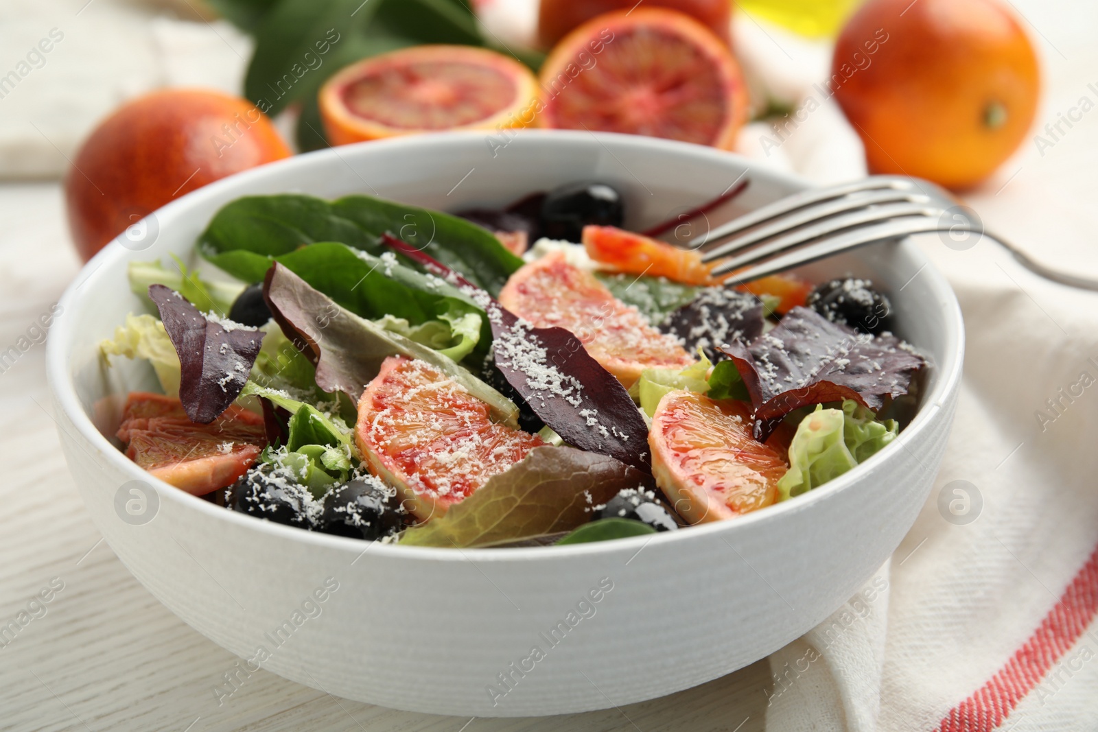 Photo of Bowl of delicious sicilian orange salad on white wooden table, closeup