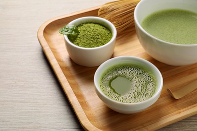 Fresh matcha tea, bamboo whisk and green powder on wooden table, closeup