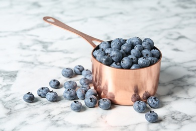 Photo of Cookware with juicy and fresh blueberries on marble table