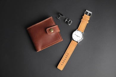 Photo of Stylish wrist watch, cuff links and wallet on black background. Fashion accessory