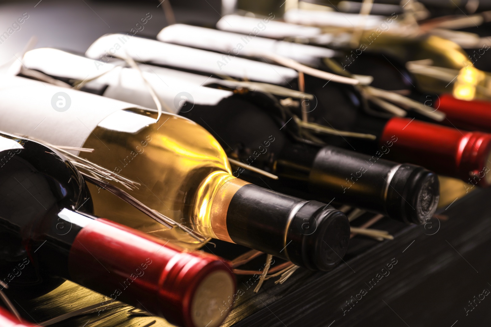 Photo of Bottles with delicious wine on shelf, closeup. Professional sommelier