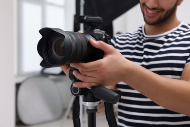Photo of Professional photographer with camera in modern photo studio, closeup