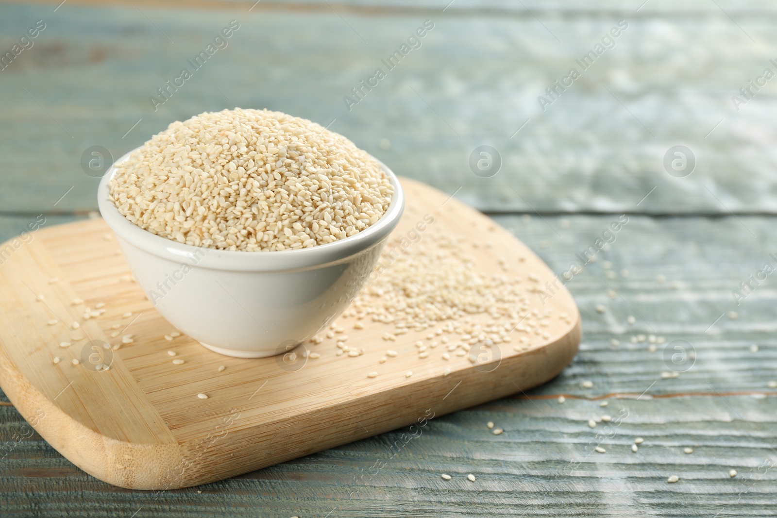 Photo of White sesame seeds on light blue wooden table