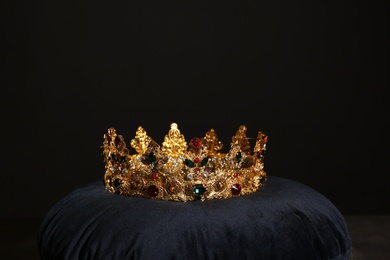 Photo of Beautiful golden crown on black velvet pillow. Fantasy item