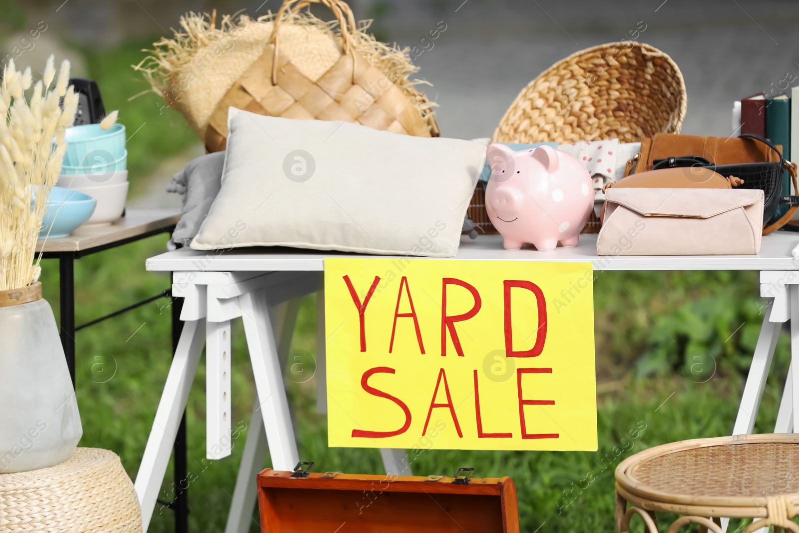 Photo of Table with different stuff and sign Yard sale outdoors