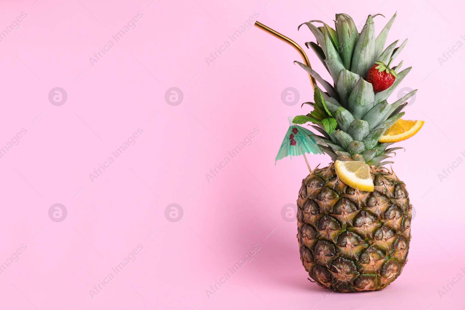 Photo of Fresh pineapple decorated with fruits and straw as summer cocktail on color background, space for text