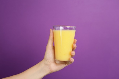 Woman holding glass with delicious smoothie on color background