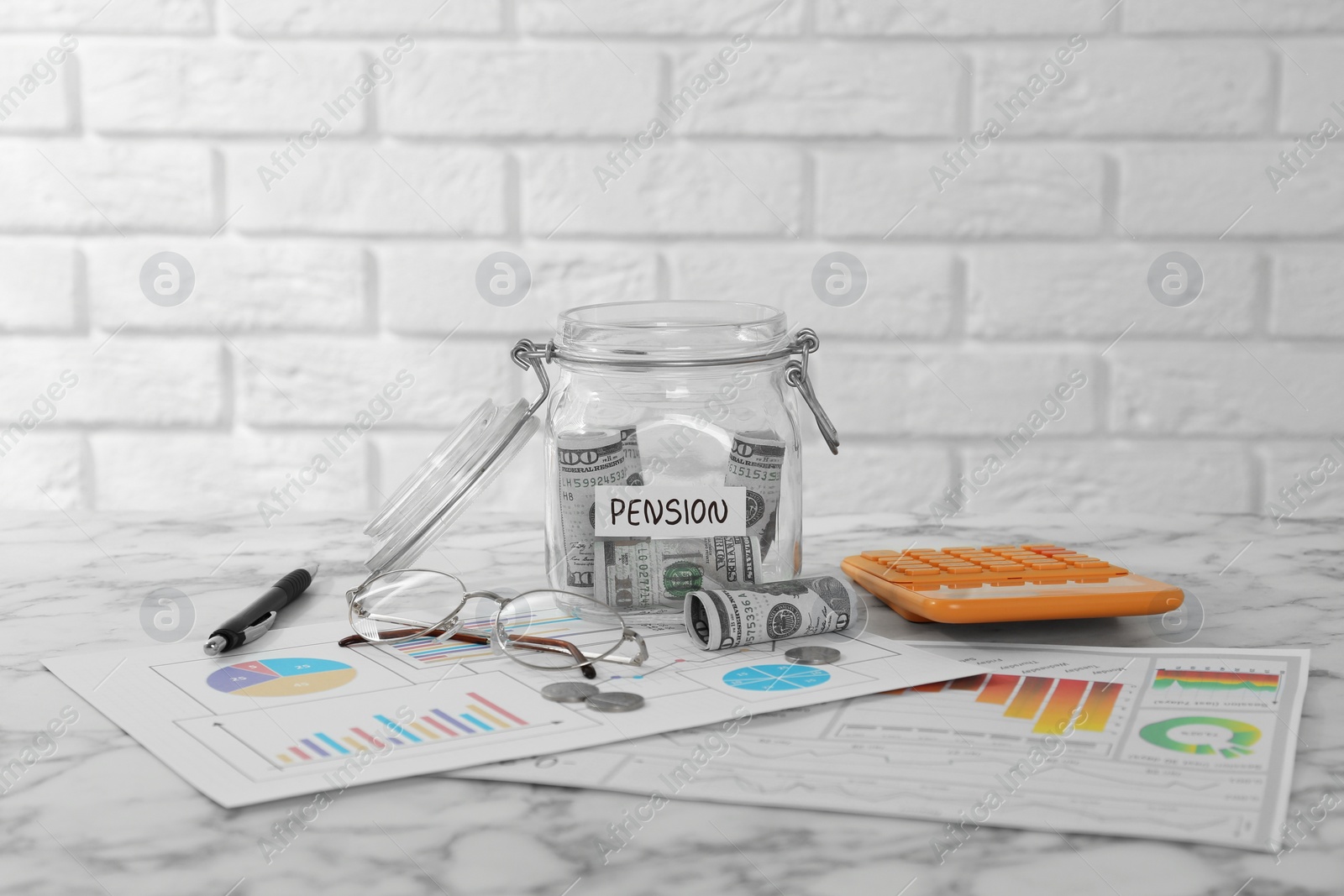 Photo of Glass jar with word Pension, money, calculator, charts and glasses on marble table