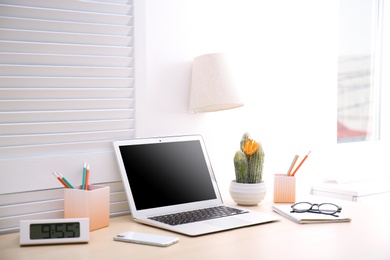 Photo of Modern workplace with laptop on table. Blank screen for mockup