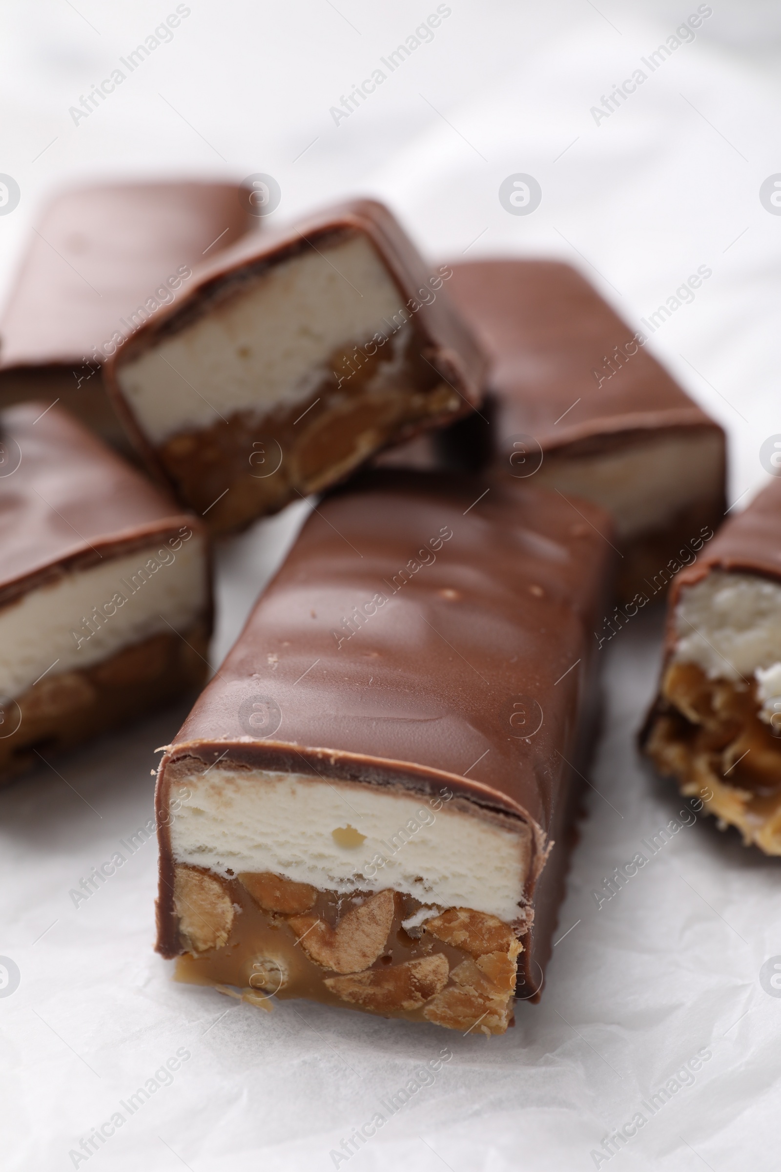 Photo of Tasty chocolate bars with nougat and nuts on white table, closeup