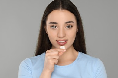 Happy young woman with bubble gums on grey background