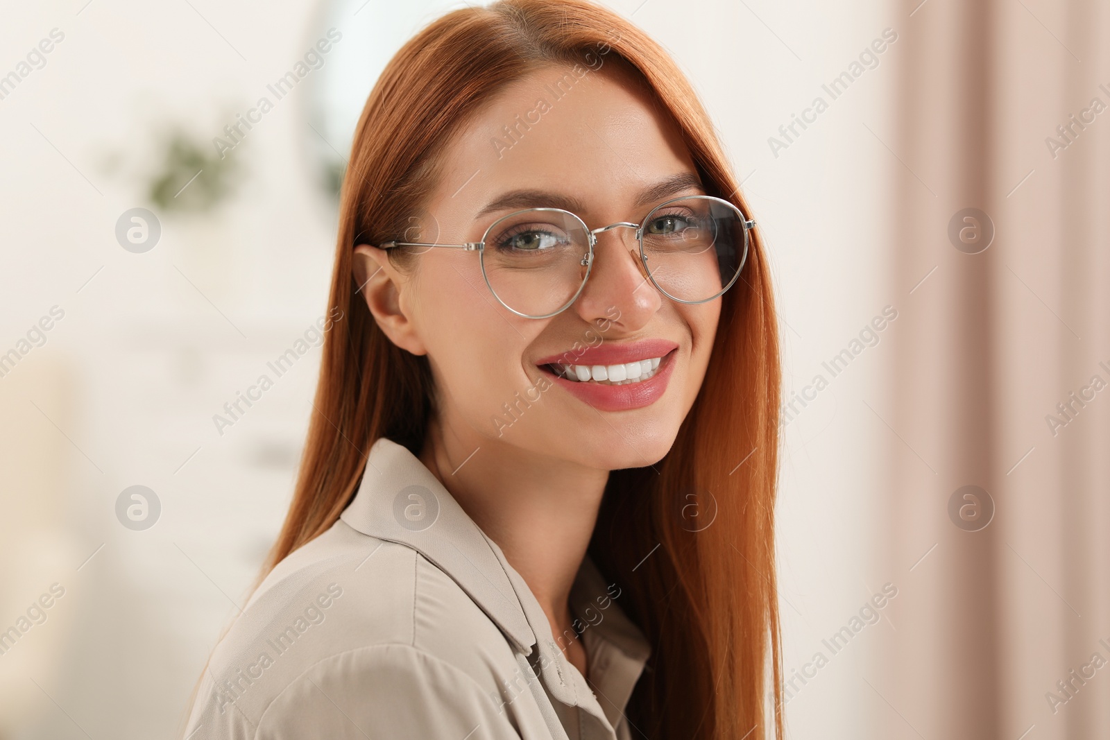 Photo of Portrait of beautiful young woman with red hair indoors. Attractive lady smiling and looking into camera