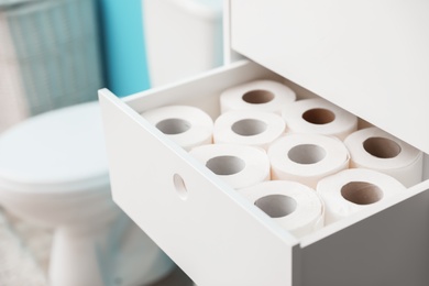 Photo of Open cabinet drawer with toilet paper rolls in bathroom