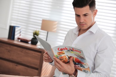 Photo of Man reading new culinary magazine in room