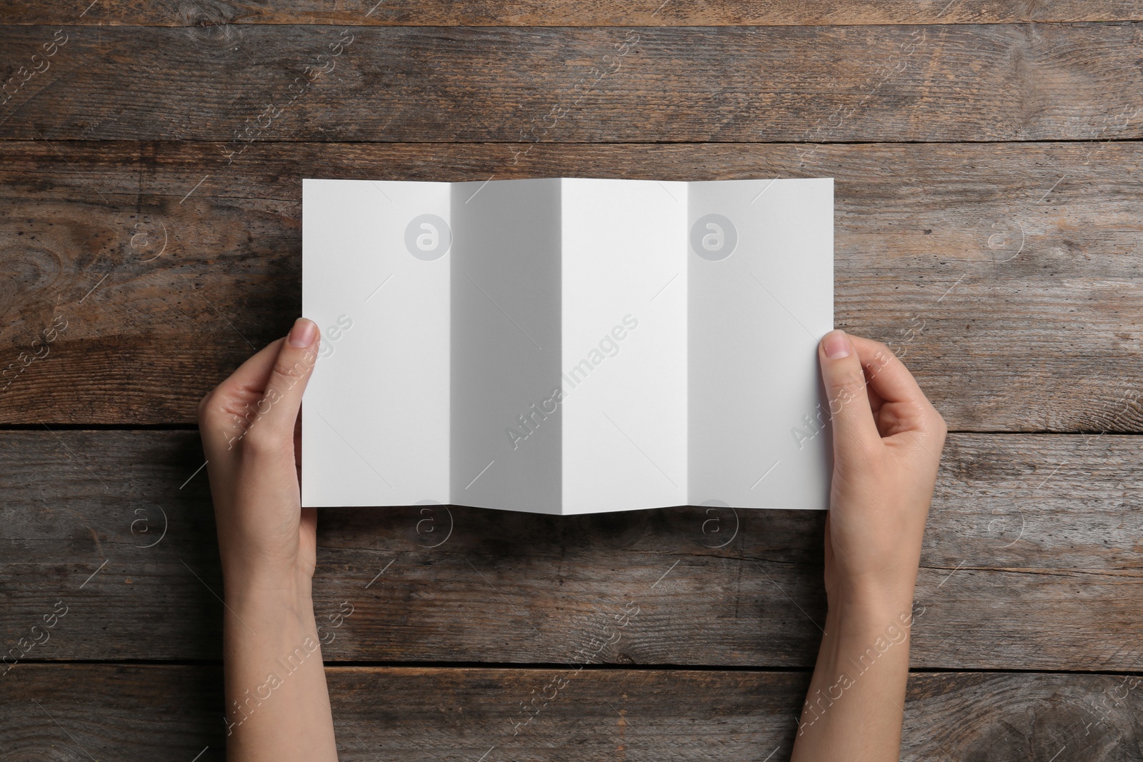 Photo of Woman with blank brochure on wooden background, above view. Mock up for design