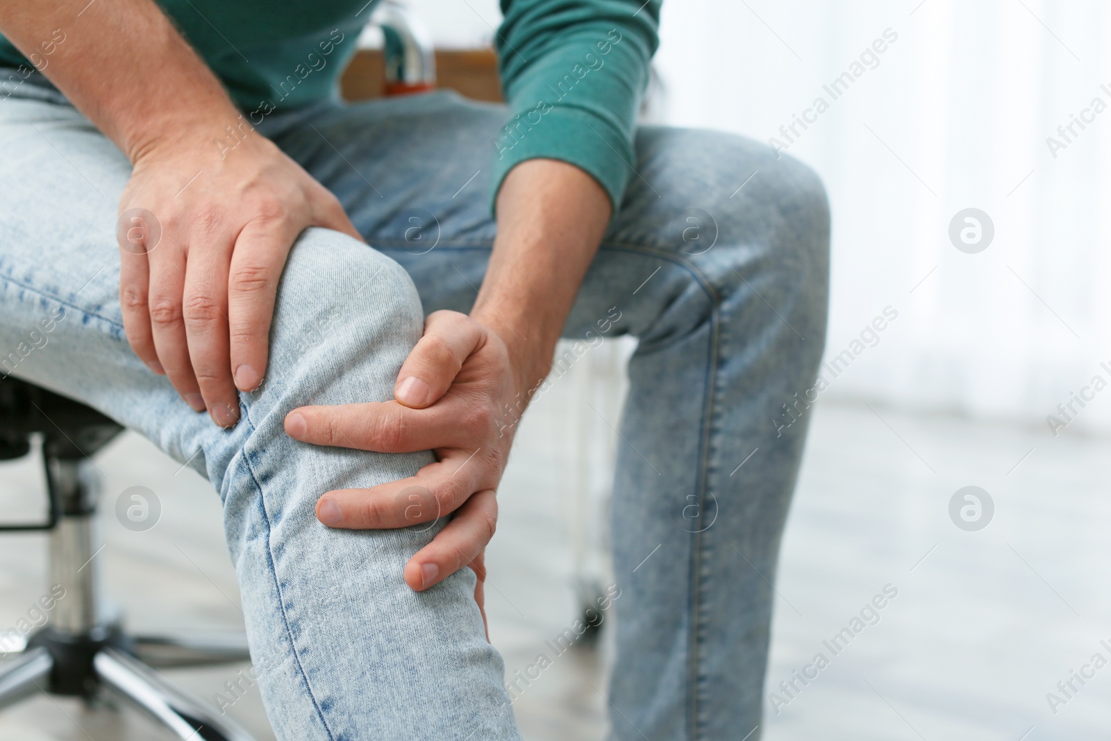 Photo of Man suffering from leg pain indoors, closeup