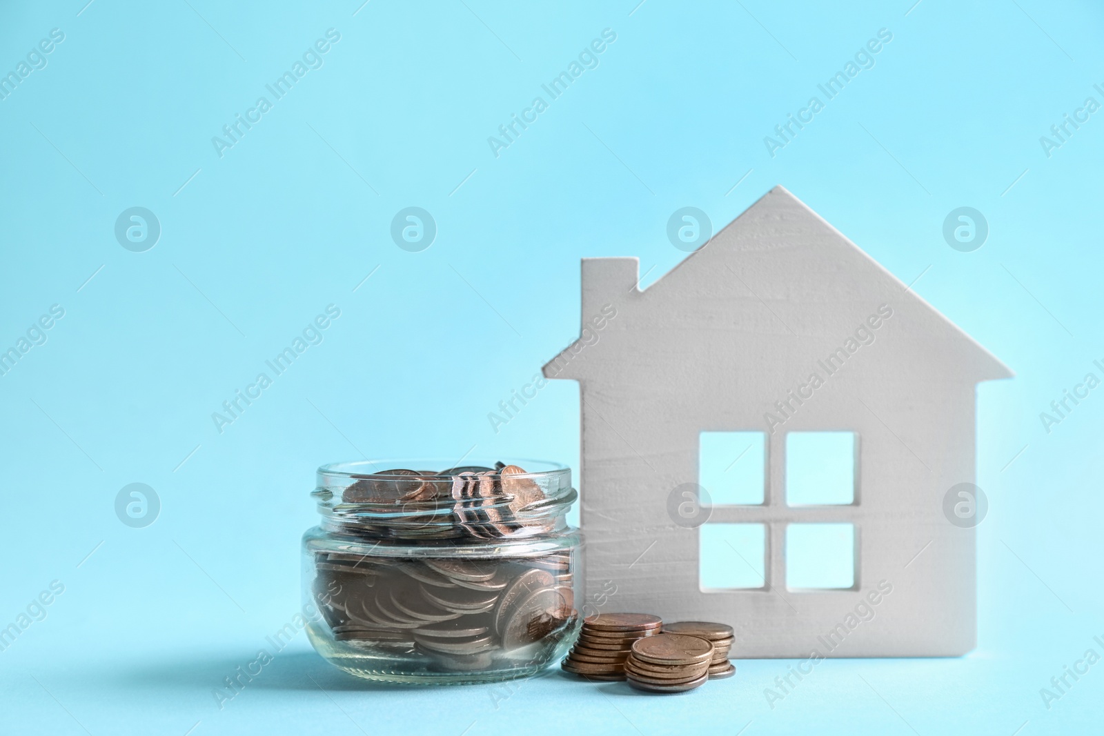 Photo of House model and jar with coins on color background. Space for text